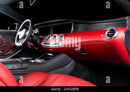 Voiture de luxe moderne rouge Intérieur avec volant, levier de vitesses et la planche de bord. Chemin de détourage. Détail de l'intérieur automobile moderne. La boîte de vitesses automatique de stick. Par Banque D'Images