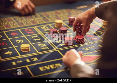 Une main avec plaquettes fait un pari sur la roulette dans un casino. Banque D'Images