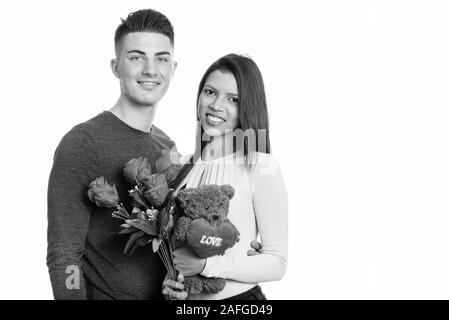 Young happy couple smiling while holding roses rouges et des ours en peluche avec coeur et amour sign Banque D'Images