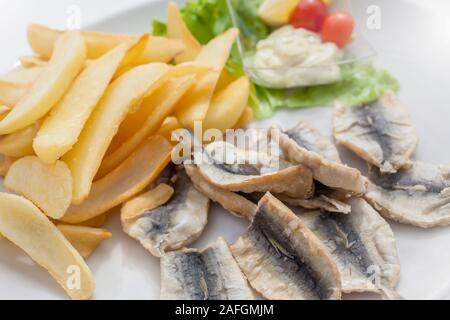 Anchois frits sur une assiette avec des frites et de l'arrière-plan la décoration, salade, tomates mayonnaise Banque D'Images