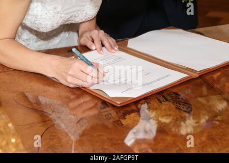 Le détail d'une cérémonie de mariage. La mariée est signaturing le document après la cérémonie avec son nouveau nom. Banque D'Images