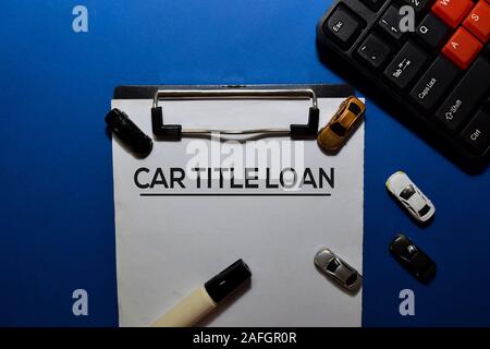 Titre de prêt voiture écrire sur le document avec des jouets voiture isolé sur fond bleu. Banque D'Images