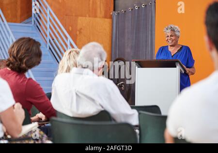 Senior Woman à Podium présider la réunion de quartier au centre communautaire Banque D'Images