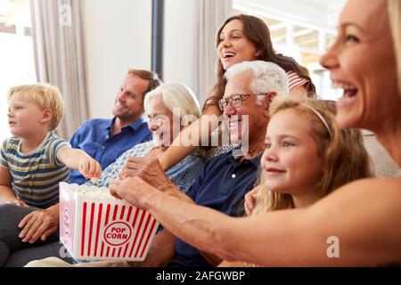 Multi-Generation Family Sitting on Sofa At Home Eating Popcorn et regarder ensemble Banque D'Images