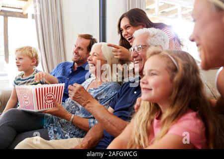 Multi-Generation Family Sitting on Sofa At Home Eating Popcorn et regarder ensemble Banque D'Images