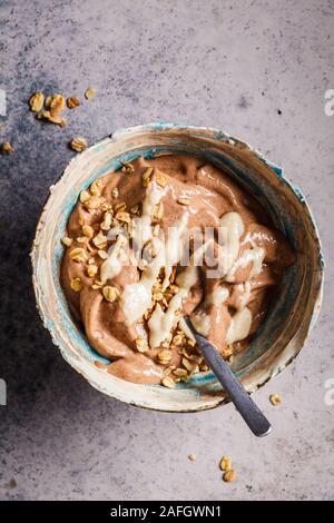 Petit-déjeuner végétalien. Banane chocolat nicecream avec granola et du beurre de cacahuètes. Banque D'Images
