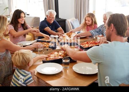 Multi Generation Family Sitting Around Table Manger ensemble de pizzas à emporter Banque D'Images