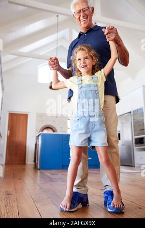 Jeu de petite-fille marche sur pieds grands-pères à la maison Banque D'Images