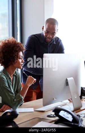 Les jeunes professionnels de la création qui travaillent ensemble à un ordinateur dans un bureau, vertical, Close up Banque D'Images