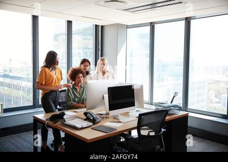 Quatre femmes créatifs travaillant autour de l'écran d'un ordinateur dans un bureau, vue pleine longueur Banque D'Images