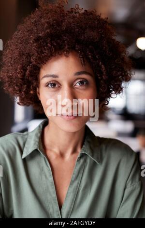 Portrait de femme noire millénaire de créativité dans un bureau à l'appareil photo légèrement souriant Banque D'Images