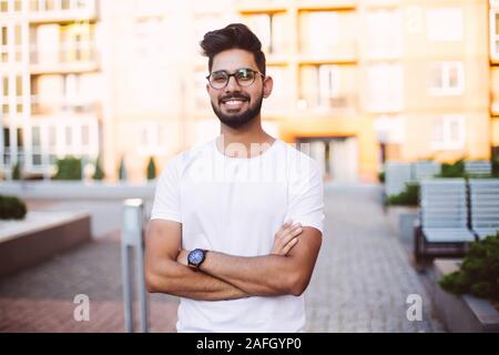 Jeune homme souriant et asiatiques à la recherche à l'appareil photo. Portrait of a happy beau jeune homme dans une rue urbaine. Banque D'Images