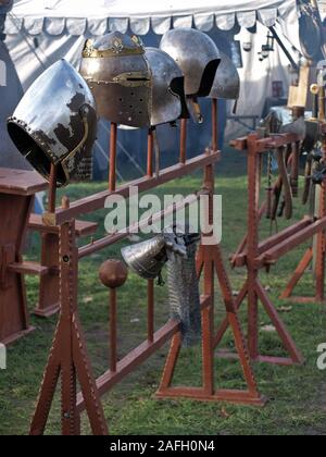 Casques de chevalier et d'armes à l'écran sur un support en bois à un marché médiéval à Mülheim Ruhr. La fumée est dans l'air.des tentes dans le fond flou Banque D'Images