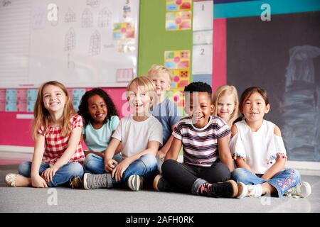 Portrait des élèves de l'Élémentaire Sitting on Floor In Classroom Banque D'Images