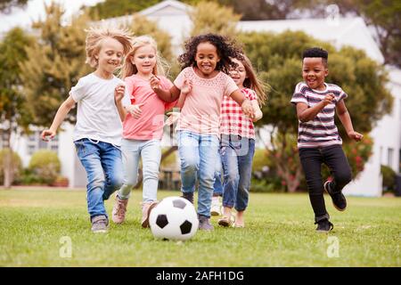 Groupe d'Enfants jouant au football avec des amis dans la région de Park Banque D'Images