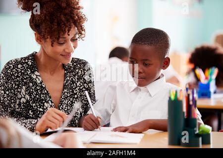 Femme Institutrice mâles en uniforme qui élève un à un soutien en classe Banque D'Images