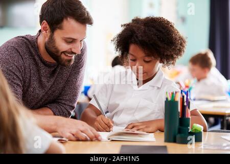 Institutrice Mâle Femelle en uniforme qui élève un à un soutien en classe Banque D'Images