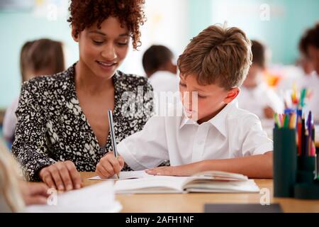 Femme Institutrice mâles en uniforme qui élève un à un soutien en classe Banque D'Images