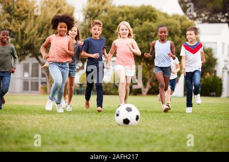 Groupe d'Enfants jouant au football avec des amis dans la région de Park Banque D'Images