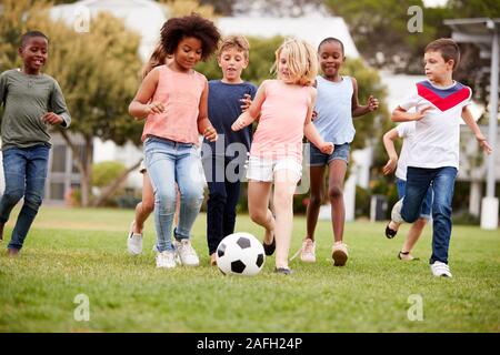 Groupe d'Enfants jouant au football avec des amis dans la région de Park Banque D'Images