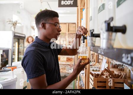 Man Filling contenant avec lave-vaisselle en poudre dans l'épicerie de plastique Banque D'Images