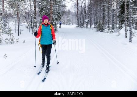 Ski de fond - Femme avec skis sur la forêt enneigée piste de ski. Akaslompolo, Finlande Banque D'Images