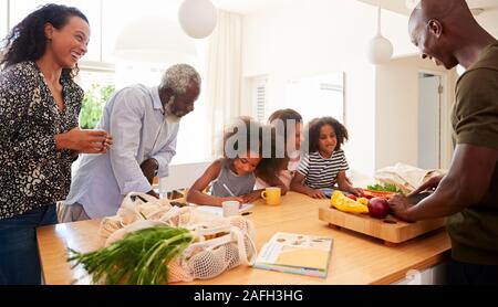 Les grands-parents assis à table avec des petits-enfants de jouer aux jeux que la famille prépare des repas Banque D'Images