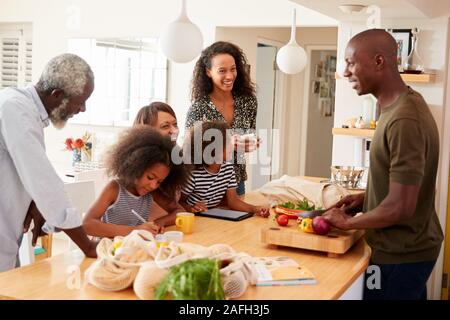 Les grands-parents assis à table avec des petits-enfants de jouer aux jeux que la famille prépare des repas Banque D'Images