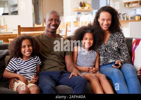 Portrait Of Smiling Family Sitting on Sofa At Home Relaxing Together Banque D'Images