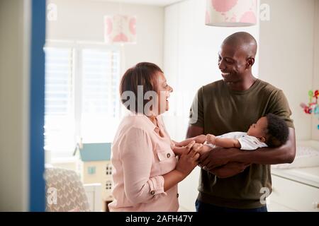 Fier grand-mère avec son petit-fils adultes de câliner Bébé en pépinière à la maison Banque D'Images