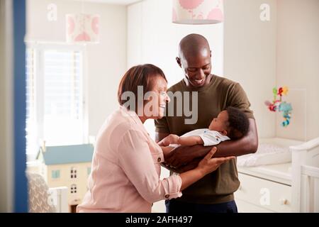 Fier grand-mère avec son petit-fils adultes de câliner Bébé en pépinière à la maison Banque D'Images