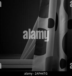 Photo en niveaux de gris d'un rideau blanc avec de gros points noirs arrière-plan sombre Banque D'Images