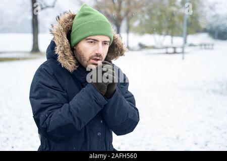 Jeune Homme En Bonnet Gris, écharpe, Gants Veste Chaude Vous Regardant Tout  En Défilant Dans Le Smartphone Le Jour De L'hiver