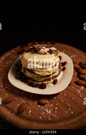 Une pile de crêpes au sirop blanc et aux amandes sur un plateau en bois recouvert de poudre à pâte Banque D'Images