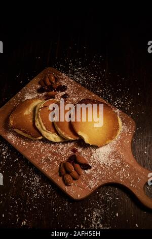Injection verticale à grand angle de crêpes et d'amandes sur un planche à découper recouverte de poudre de noix de coco Banque D'Images