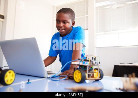 Male Student Building et de programmation Robot Véhicule en classe après l'École de codage informatique Banque D'Images