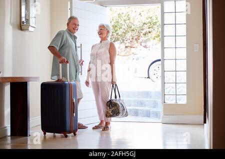 En couple avec valise porte avant sur le point de partir pour des vacances Banque D'Images