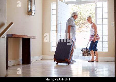 En couple avec valise porte avant sur le point de partir pour des vacances Banque D'Images