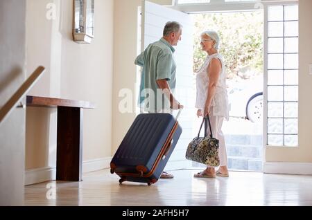 En couple avec valise porte avant sur le point de partir pour des vacances Banque D'Images