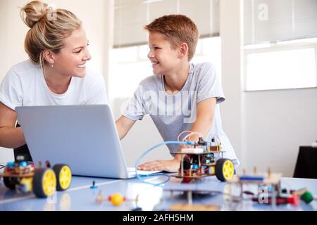 Male student with Teacher Building Robot Véhicule en classe après l'École de codage informatique Banque D'Images