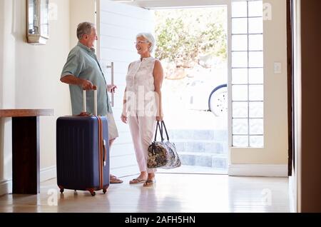 En couple avec valise porte avant sur le point de partir pour des vacances Banque D'Images