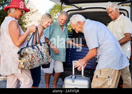 Groupe d'amis charger des bagages dans coffre de voiture sur le point de partir pour des vacances Banque D'Images