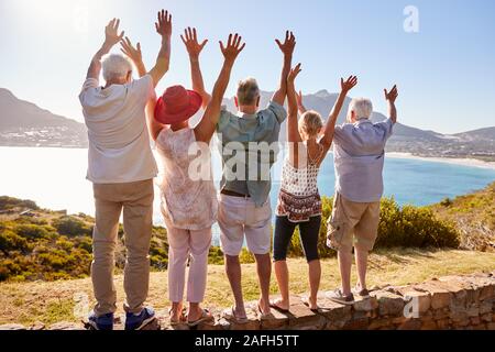 Vue arrière du Senior Friends visiter Monument sur le Groupe de vacances avec bras levés Banque D'Images