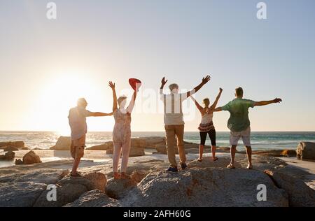 Vue arrière du Senior Friends Standing On Rocks On Vacation With Arms Outstretched Banque D'Images