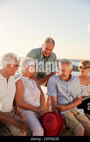 Groupe d'amis assis sur les roches par la mer sur le groupe d'été Banque D'Images