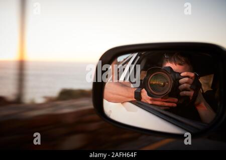 L'homme avec l'appareil photo Prendre une photo dans le rétroviseur de voiture Banque D'Images