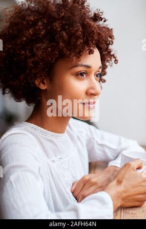 Young Woman Relaxing In Loft avec boisson chaude Banque D'Images