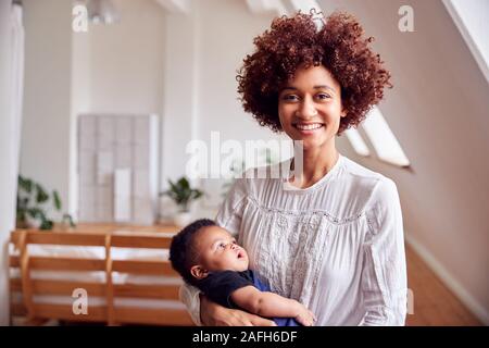 Portrait of Loving Mother Holding Newborn Baby à la maison dans cet appartement Loft