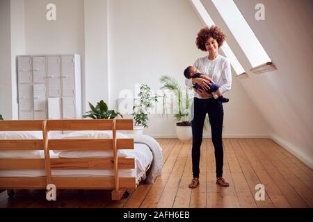 Portrait of Loving Mother Holding Newborn Baby à la maison dans cet appartement Loft Banque D'Images
