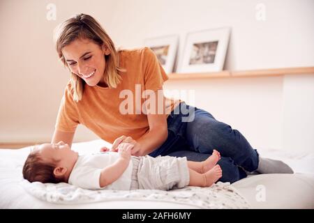Mère aimante avec nouveau-né Baby Lying On Bed At Home in Loft Apartment Banque D'Images